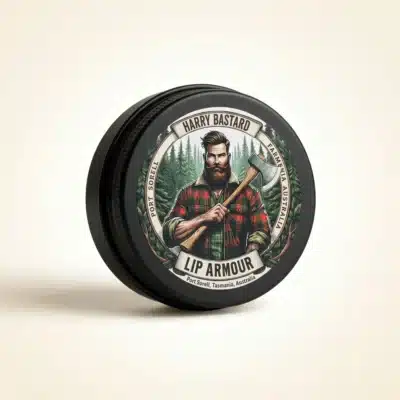 Closed black tin of Harry Bastard Lip Armour heavy-duty natural beeswax lip balm by Frogmouth Ponds, lumberjack lid artwork, Port Sorell Tasmania
