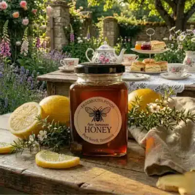 Jar of Frogmouth Ponds Pure Tasmanian Honey on an outdoor garden table with fresh fruit and honeycomb