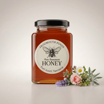 Jar of Frogmouth Ponds raw Tasmanian Garden Blend multiflora honey, rich amber colour, with a posy of cottage-garden flowers, black lid and cream label, Port Sorell Tasmania