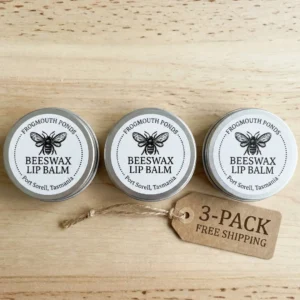 Three tins of Tasmanian Beeswax Lip Balm on a wooden table with Free Shipping tag