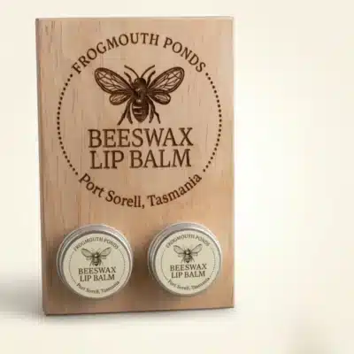 Wooden Frogmouth Ponds display board with engraved bee logo and two 12 g tins of natural Tasmanian beeswax lip balm, Port Sorell Tasmania